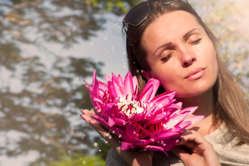 Mastering the First Impression: Your intriguing post title goes here A beautiful woman with closed eyes holding pink lotus flowers in sunlight.